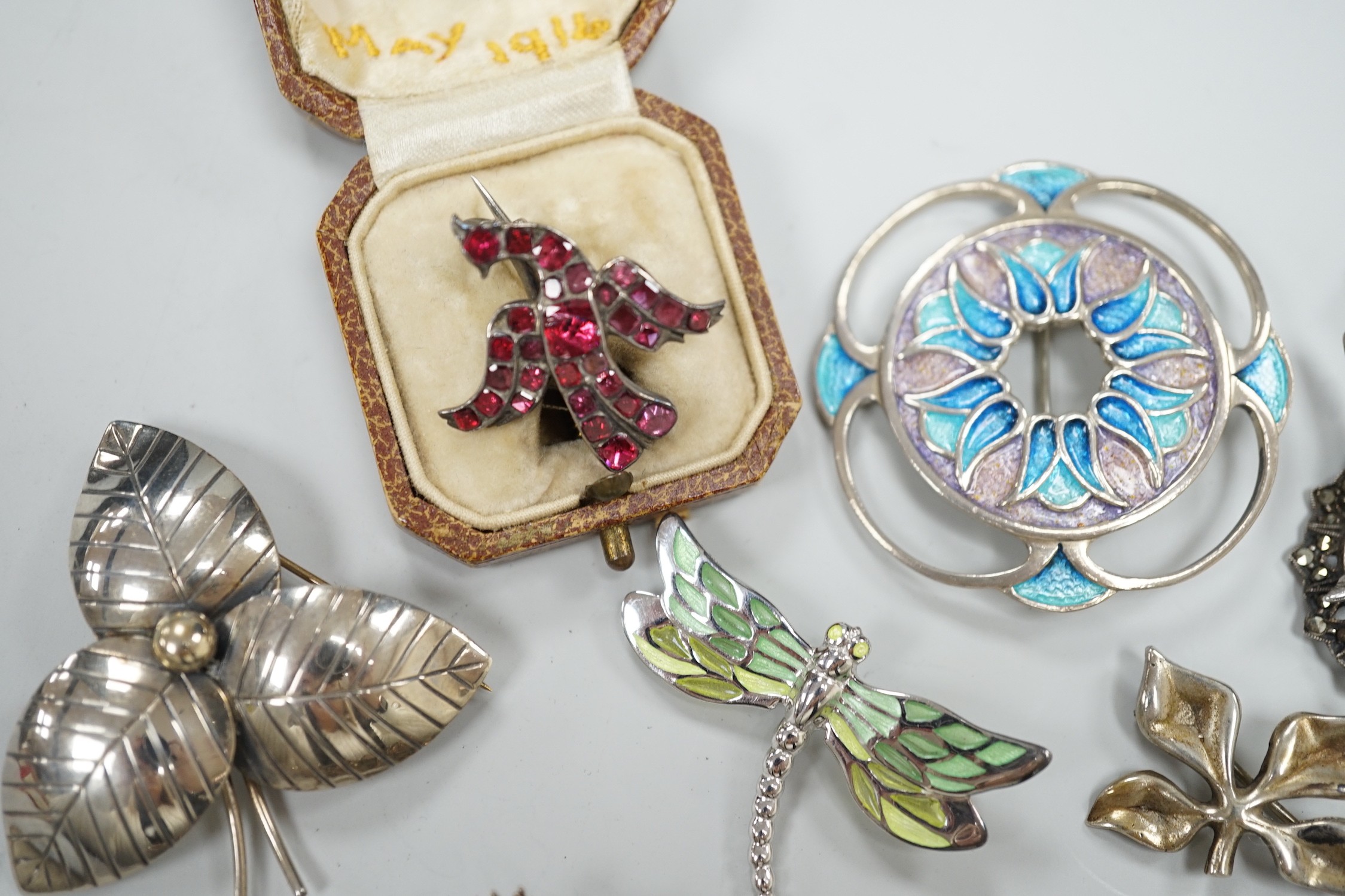 An early 20th century white metal and foil backed garnet cluster set bird brooch, 27mm and eight other assorted mainly 925 brooches including two enamelled and one Finnish yacht brooch.